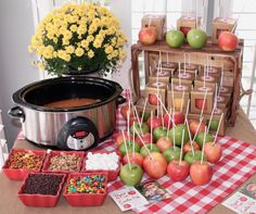 an assortment of apples and candies on a table next to a crock pot