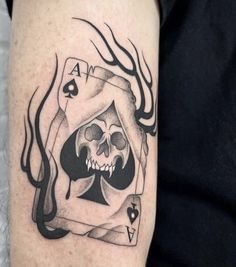 a black and white photo of a skull playing card tattoo on the right upper arm