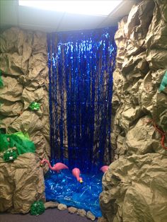 a fake waterfall with blue water and plastic streamers in the center, surrounded by rocks