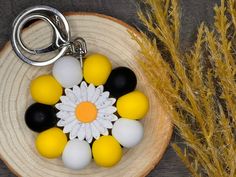 a keychain with several different colored eggs and a flower on it next to some dry grass