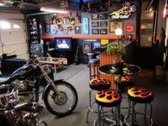 a motorcycle is parked in a garage next to some stools and tables with chairs around them