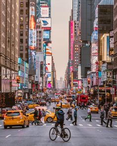 a busy city street filled with lots of traffic and people crossing the street in front of tall buildings