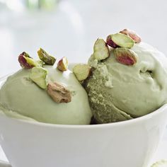 two scoops of green tea ice cream in a white bowl with pistachio leaves on top