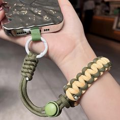 a hand holding a cell phone with a green bracelet on it