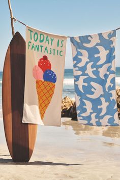 two towels hanging from a clothes line with an ice cream cone on the beach next to it