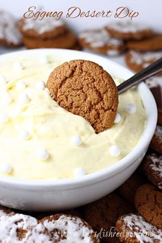 a cookie in a bowl with cream cheese on top and cookies around it to the side