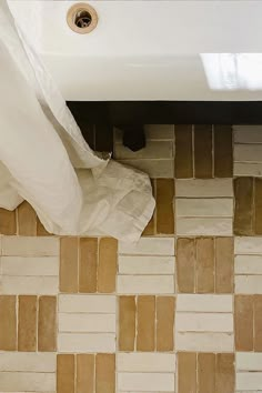 a white toilet sitting next to a bath tub in a bathroom under a window on top of a tiled floor