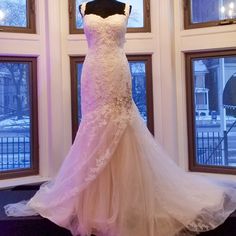 a wedding dress on display in front of windows