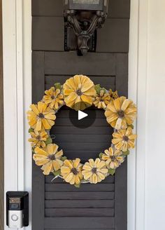 a wreath with yellow flowers hanging on the front door