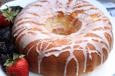 a bundt cake with icing and berries on the side sitting on a plate