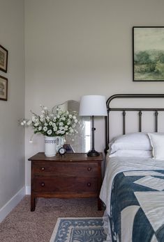 a bedroom with a bed, nightstand and pictures on the wall