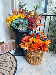 a basket filled with flowers sitting on top of a door mat next to a potted plant