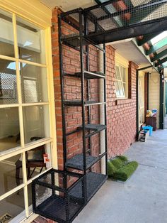 a black metal shelf sitting on the side of a brick building next to a window