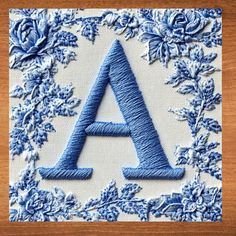 an embroidered letter with blue flowers and leaves