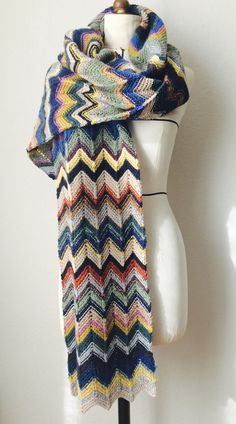 a white mannequin wearing a multicolored knitted scarf