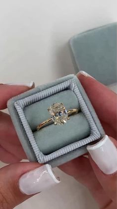 a woman's hand holding an engagement ring in a box