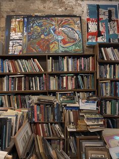 a bookshelf filled with lots of books next to a wall covered in pictures