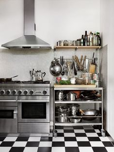 a kitchen with black and white checkered flooring, stainless steel appliances and open shelving