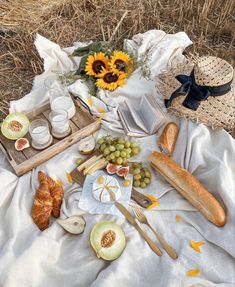 a table topped with bread, grapes and other food on top of a white blanket