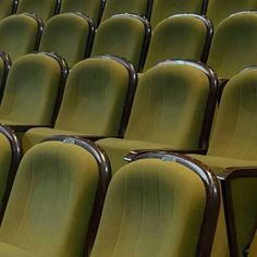 rows of green chairs in an auditorium or theater setting with no people sitting on the seats