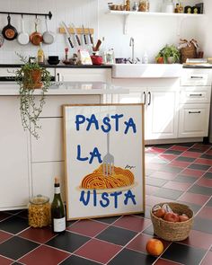 a sign that says pasta la vista next to some fruit on the floor in a kitchen