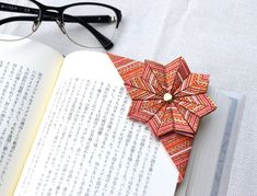 an open book with paper origami flowers on it next to eyeglasses