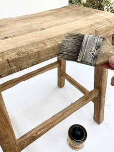 a person holding a paintbrush over a wooden bench