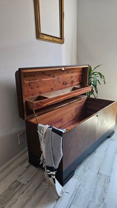 an old wooden chest sitting on top of a hard wood floor next to a potted plant