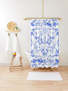 a blue and white shower curtain in a bathroom with wooden flooring next to a bathtub