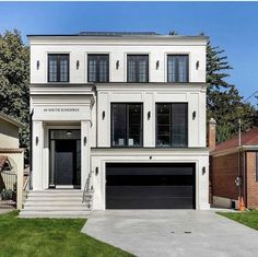 a white two story house with black garage doors