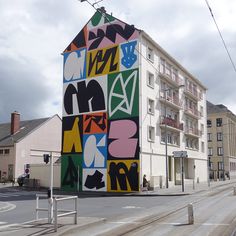 a multicolored building on the corner of a street with buildings in the background