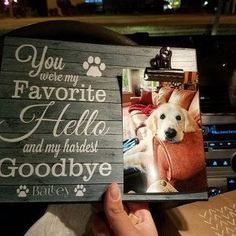 a person holding up a wooden photo frame with a dog on it's side