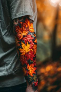 a man's arm with colorful leaves on it and the colors of autumn in the background