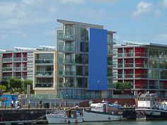 two boats are docked in the water next to some tall buildings with balconies