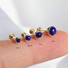 three different sized lapel pins sitting on top of a finger