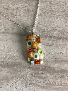 "Fused glass pendant necklace with green, white and orange murrini. The pendant is approximately .75\" x 1.50\" and comes on a 18\"chain and lobster clasp.   Caring for fused glass jewelry: To clean, use a soft cloth. Do not use harsh chemicals to clean. Should not be submerged in water, and should be removed when bathing. While fused glass is much stronger, use care when handling as can still break if dropped on hard surface.  Please contact me with any questions, changes or modifications.  Tha Freeze And Fuse, Fused Glass Pendant Necklace, Fusing Glas, Fused Glass Necklace, Fused Glass Pendant, Fused Glass Jewelry, White And Orange, Glass Pendant Necklace, Hard Surface