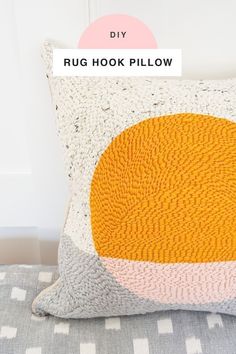 a pillow with an orange and yellow circle on the front sitting on top of a bed