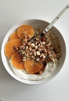 a bowl filled with oatmeal, orange slices and nuts