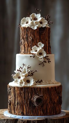 a three tiered wedding cake with white flowers on the top and brown wood grain