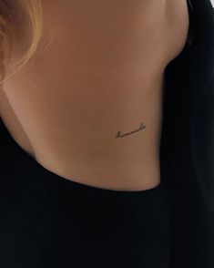 the back of a woman's neck with a small tattoo on her left side