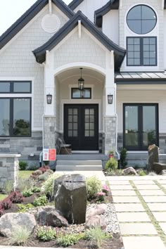 the front entrance of a house with landscaping and rocks on the ground in front of it