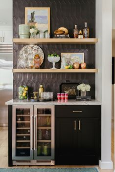 a kitchen with black cabinets and shelves filled with wine bottles, glasses, and other items