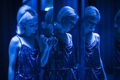 three women in sequin dresses are looking at their reflection in the mirror while one woman is brushing her hair