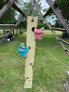 a wooden pole with two buckets hanging from it's side in the grass