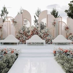 an outdoor ceremony with white benches and flowers