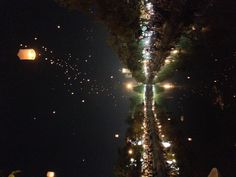 many lanterns floating in the air over a river at night