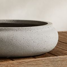 a cement bowl sitting on top of a wooden table