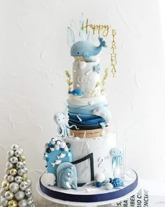 a three tiered cake decorated with blue and white decorations on top of a table