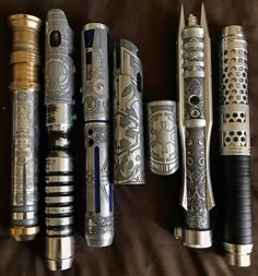 there are many different types of pens lined up together on the bed, one is black and gold