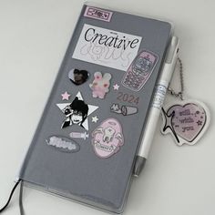 a notebook with some stickers on it and a cell phone attached to the cover